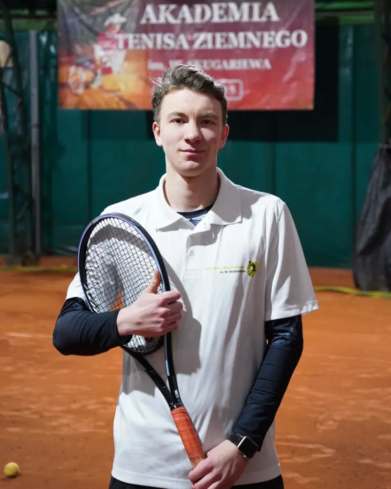 Mężczyzna trzymający rakietę tenisową na korcie tenisowym, gotowy do gry.