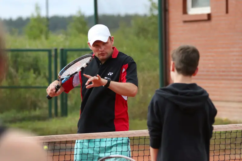 Mężczyzna trzymający rakietę tenisową, gotowy do gry na korcie.