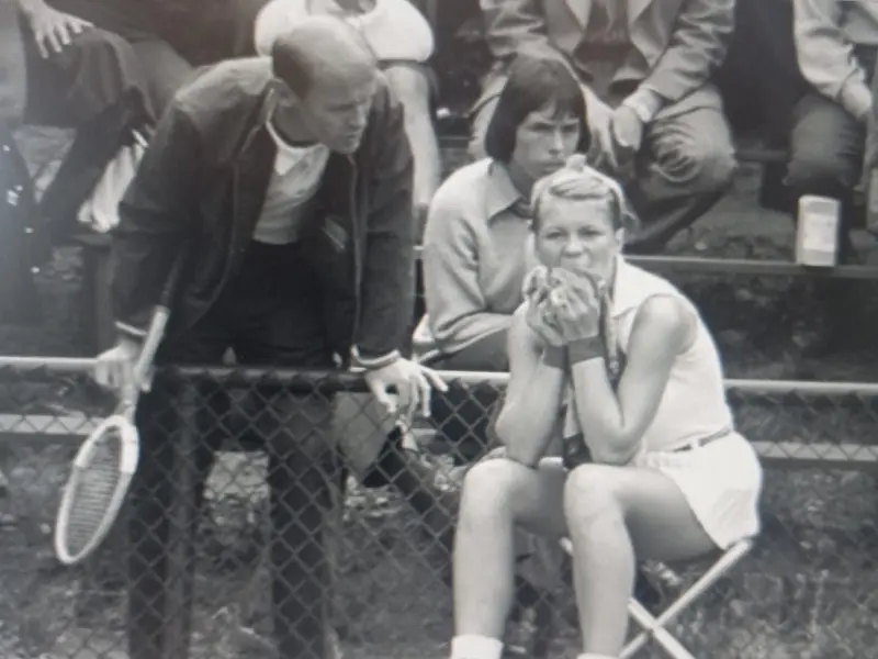 Kobieta siedząca na krześle, obok trener tenisa ziemnego.