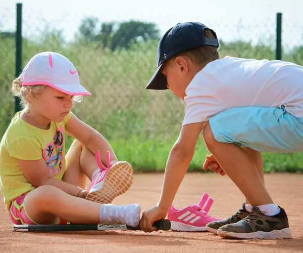 Dwójka małych dzieci na korcie tenisowym.